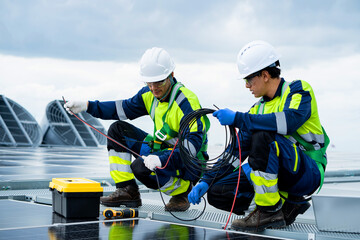 Two men in safeTwo men in safety gear are working on a solar panelty gear are looking at a laptop