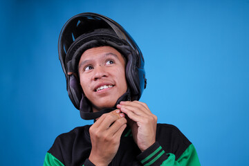 Closeup of Young Indonesian Ojol Driver Buckling His Helmet Chin Strap Looking up and Smiling