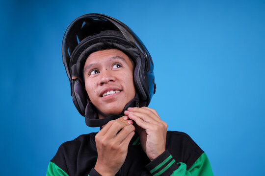 Closeup of Young Indonesian Ojol Driver Buckling His Helmet Chin Strap Looking up and Smiling