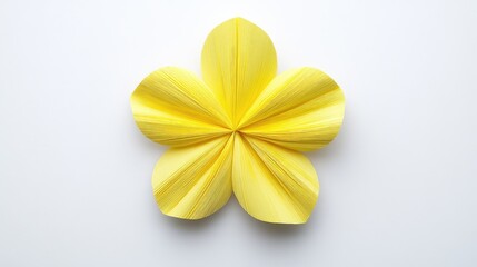 Delicate origami flower with layered petals in vibrant yellow on a pristine white background showcasing craftsmanship and artistry