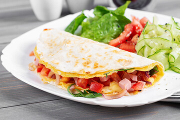Healthy breakfast. Quesadilla with omelet, ham, cheese, and tomatoes.