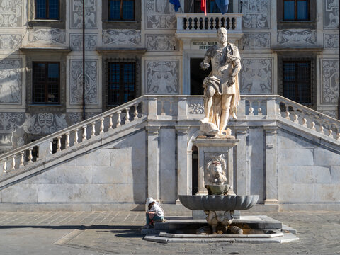 Palazzo della Carovana's ornate sgraffito facade and grand marble staircase face Piazza dei Cavalieri in Pisa, with Cosimo I de' Medici's statue and a central fountain nearby