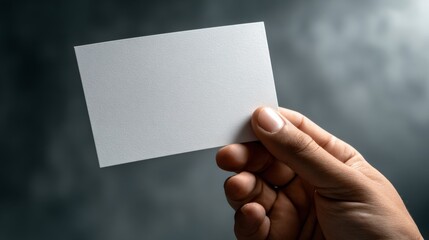 A close-up of a hand holding a blank card against a softly blurred background, ideal for mockups or personal use.