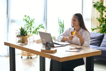 Woman with Waardenburg syndrome enjoys remote work while sipping tea at home