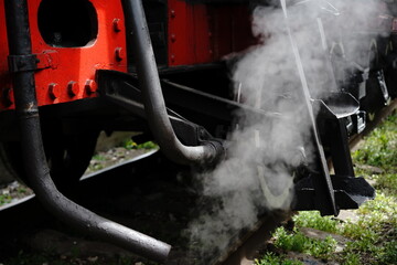 Steam rises from the machinery of a vintage train at a railway station in early morning light