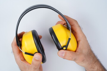 Hands holding yellow ear protection gear suitable for loud environments