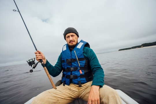 Man sitting on boat fishing with fishing rod