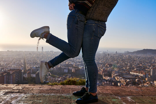 Legs of boyfriends standing on observation point with cityscape in background, Bunkers del Carmel, Barcelona, Spain