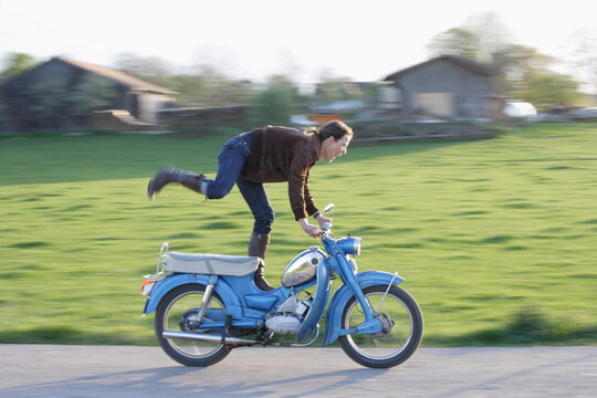 Germany, Bavaria, Mature woman riding old moped of 1960s