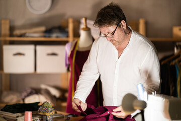 Middle-aged male dressmaker reviewing jeans to restore