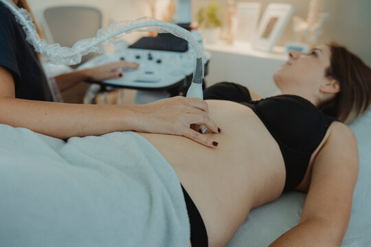 Doctor doing ultrasound on pregnant woman lying in clinic