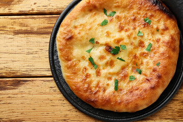 Delicious Megrelian khachapuri with parsley on wooden table, top view. Space for text
