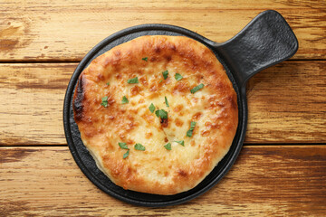 Delicious Megrelian khachapuri with parsley on wooden table, top view