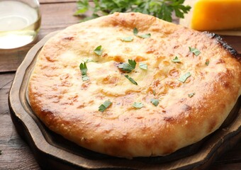 Delicious Megrelian khachapuri with ingredients on wooden table, closeup
