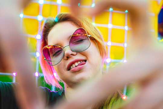 Girl in sunglasses at amusement park with neon lights and playful mood