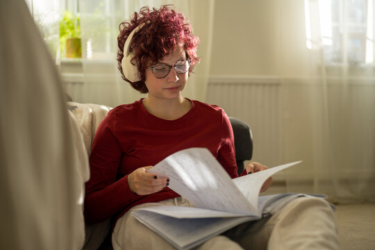 Teenager with red curly hair studying and writing homework indoors