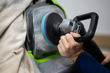 Worker restoring car headlight using polishing machine