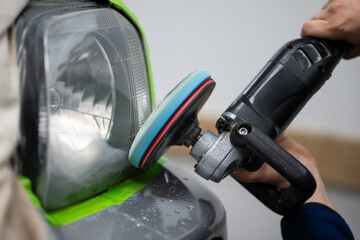 Person polishing car headlight with power buffer © Zoran Jesic