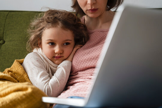 Mother with sick daughter using laptop at home