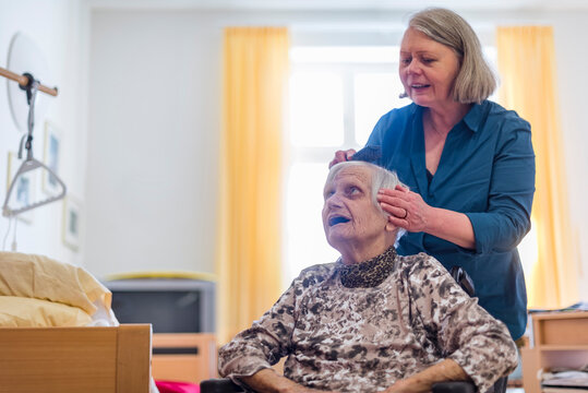 Woman taking care of old woman brushing her hair