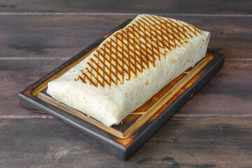 Tacos lyonnais &ndash; sp&eacute;cialit&eacute; fran&ccedil;aise de street food halal, garni de viande, frites et sauce, pr&eacute;sent&eacute; sur une table de restauration rapide