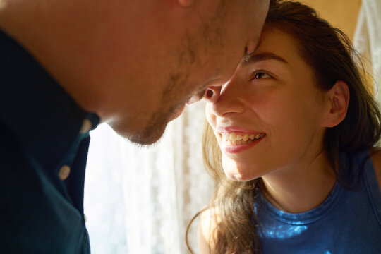 Playful couple smiling and hugging at home in warm light
