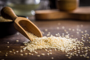 Roasted sesame seeds in scoop on wooden table.