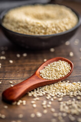 Roasted sesame seeds on spoon on wooden table.