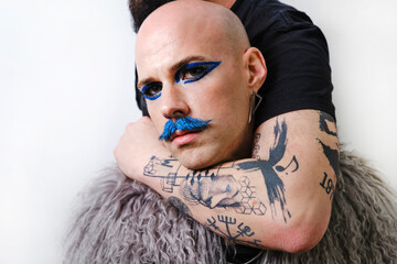 Man cuddling arm around young male against white background