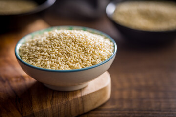 Roasted sesame seeds in bowl on wooden table.