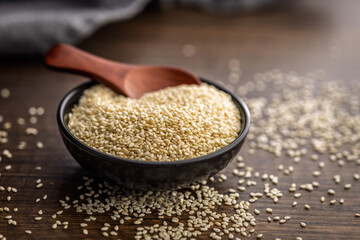 Roasted sesame seeds in bowl on wooden table.