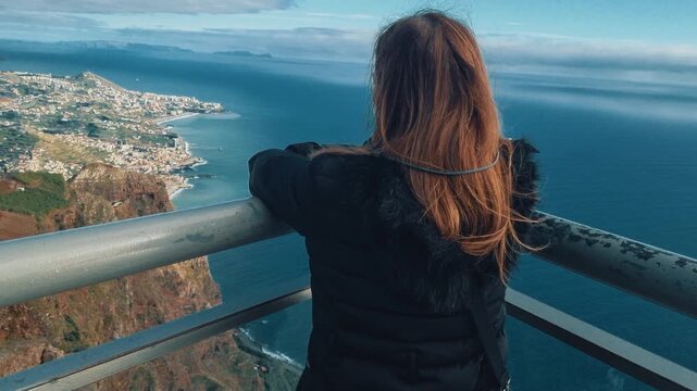 woman looking at the ocean and landscape from the Cabo Girao skywalk in Madeira, Portugal