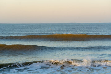 Tranquil ocean scene featuring evenly breaking waves under the gentle glow of early morning light. 