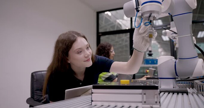 female technician programs collaborative robot arm in slowmotion demonstration using gloves and tablet in automation training session inside smart manufacturing workshop under industry40 concept