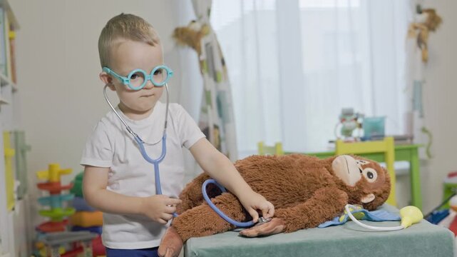 Little veterinarian boy treating stuffed monkey toy