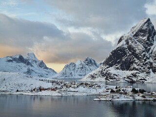 Reine, Norway. Banner of beautiful village Reine among mountain peaks, located on Lofoten Islands Archipelago in Norway. Seasonal snowy winter panoramic view. Picturesque Norwegian polar landscape.
