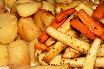 Close up of roasted vegetables crsipy potatoes parsnip and carrots side dish for Sunday roast dinner