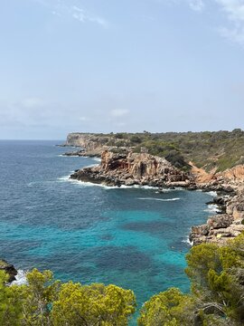 Enseada paradis&iacute;aca com mar turquesa e fal&eacute;sias rochosas vistas entre pinheiros.

Paradise cove with turquoise sea and rocky cliffs framed by pine trees