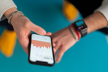 From above of crop unrecognizable guy browsing tracking data in app on screen of modern mobile phone in selective focus after fitness training