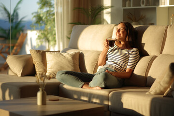 Obraz premium Happy woman laughing alone drinking coffee at sunset