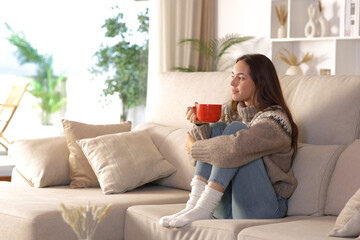 Woman in winter drinking coffee looking through a window