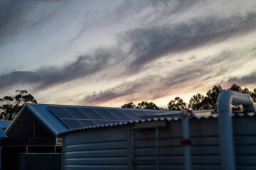 Passive solar new sustainable house with solar pannels on roof at sunset with rainwater reservoir...