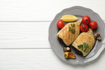 Pieces of tasty grilled squid stuffed with mushrooms, parsley and vegetables on white wooden table, top view. Space for text