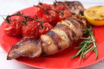 Tasty stuffed squid, rosemary, lemon and tomatoes on white table, closeup
