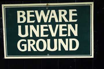 Obraz premium Close-up of a Beward Uneven Ground sign warning pedestrians of potential hazard in outdoor area.