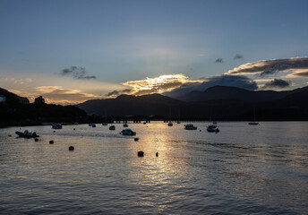 Morning light over Barmouth Bridge with boats moored on the estuary