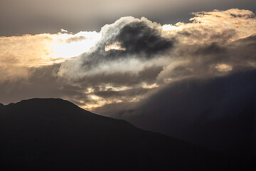Morning sun obscured by dramatic clouds above mountain slopes near Barmouth