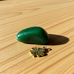 Green Aventurine Stone and Clover Charm on Wooden Surface.