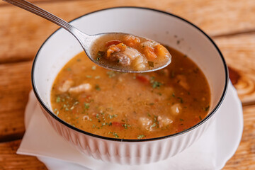 Hearty goulash stew with tender meat and vegetables in a white bowl, warm comfort food served on rustic wooden table