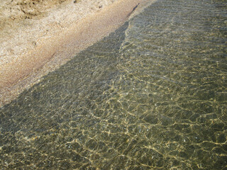 Beautiful clear water reflecting sunlight along the peaceful coastal shore